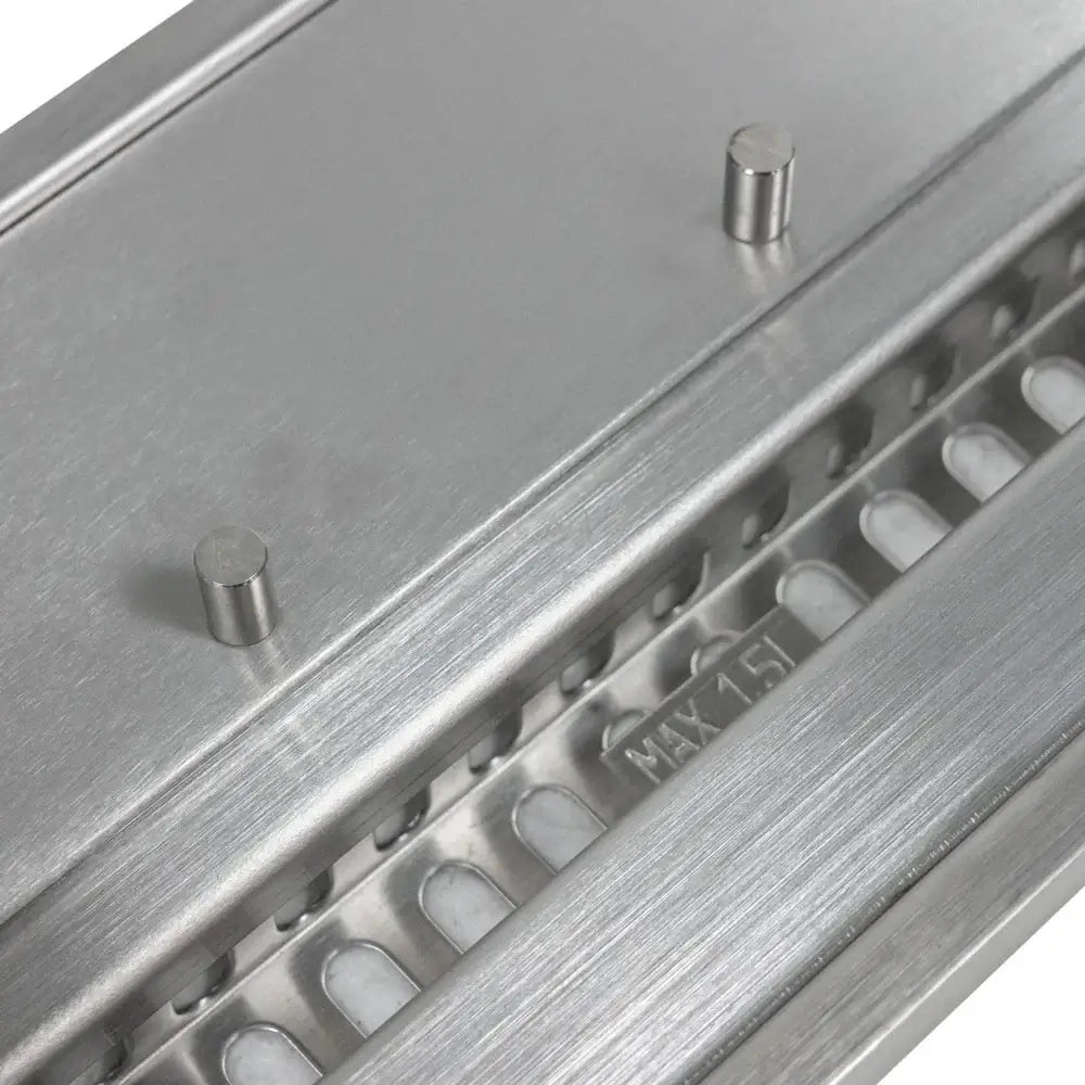 Close-up of stainless steel surface with two small pins and ventilation slots for a bioethanol burner.