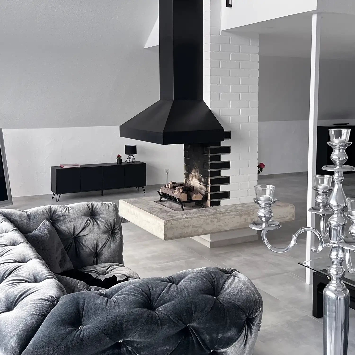 Modern living room featuring a freestanding Bioethanol Fire Grate with a sleek black chimney above a stylish sofa.