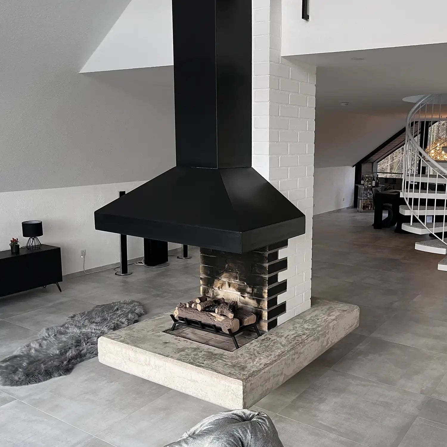Modern black chimney and bioethanol fire grate in a stylish living room with minimalist decor.