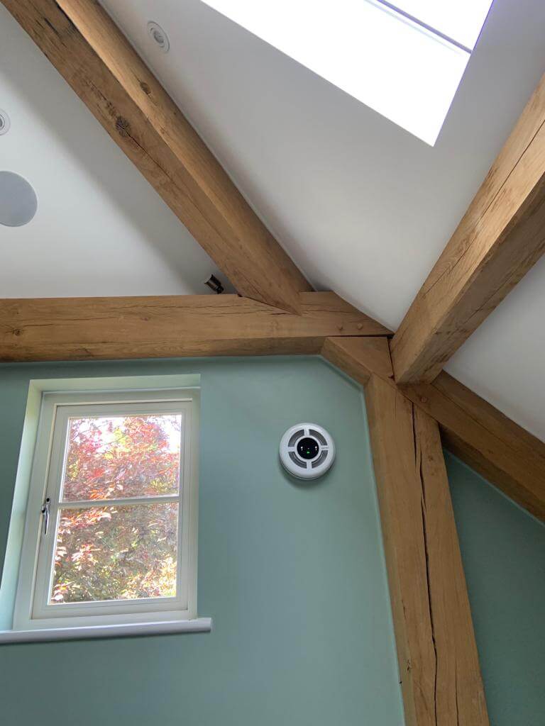 Interior view showing wooden beams and a heat recovery ventilator near a window in a modern home.