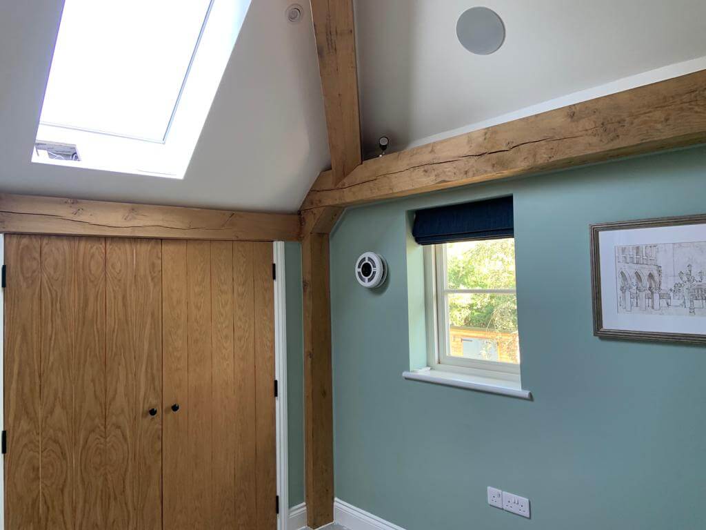 Modern room interior featuring a heat recovery ventilator, skylight, and natural wood beams.