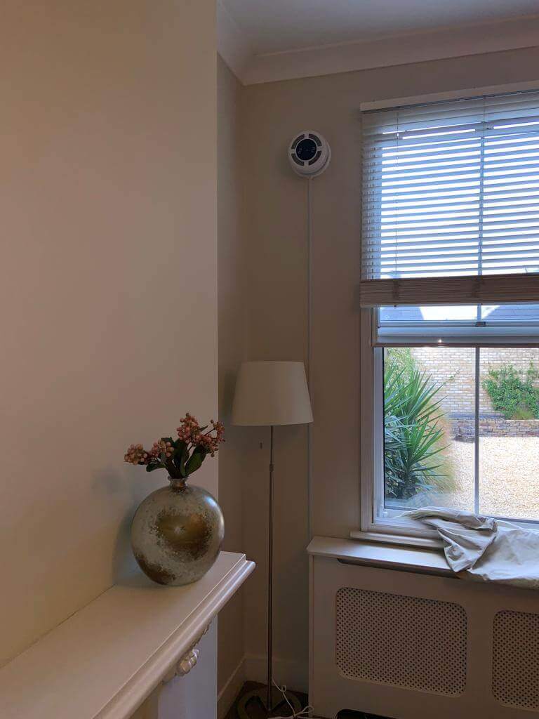 Interior view of a room featuring a modern heat recovery ventilator, lamp, and window with natural light.