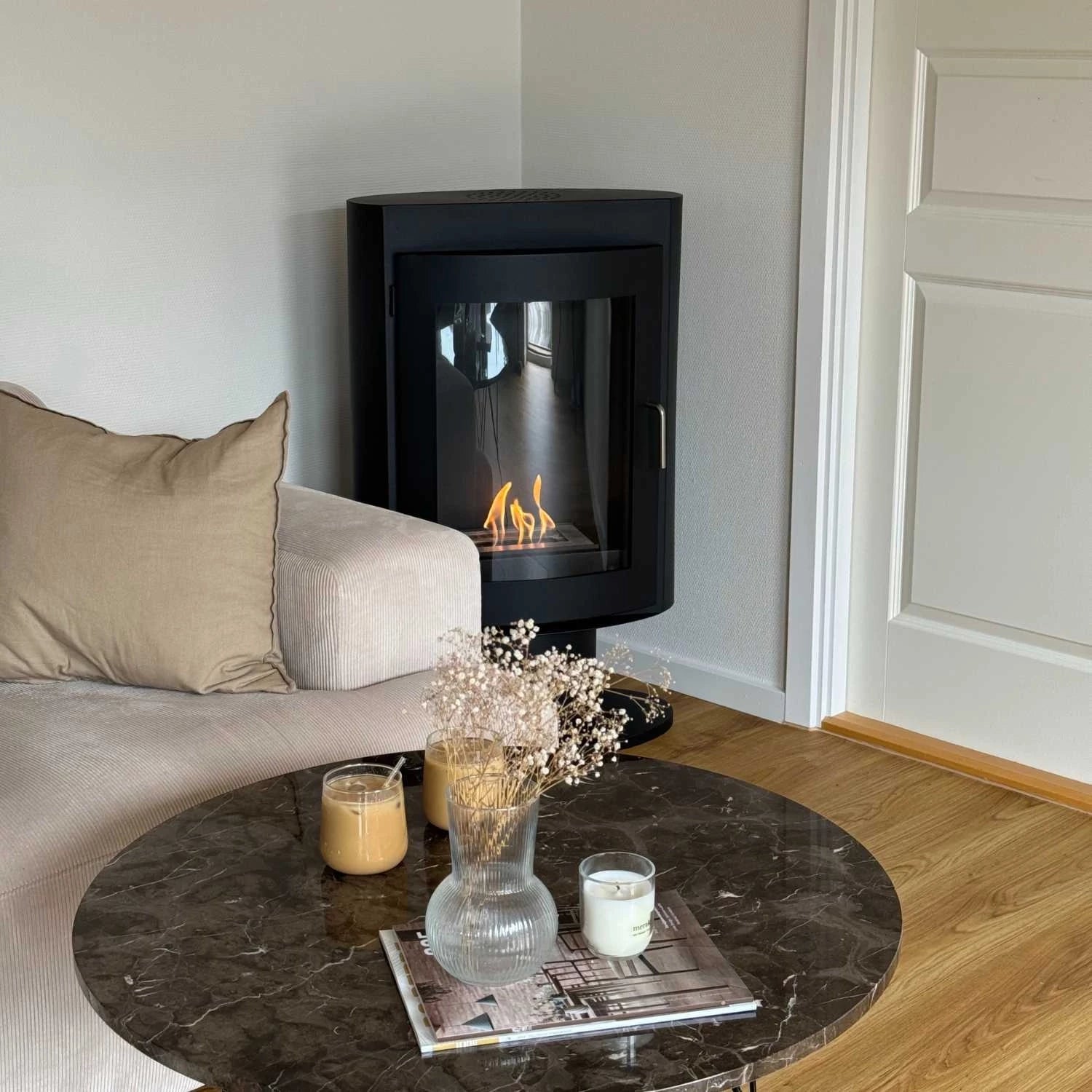 Cozy living room featuring the Trenton bioethanol stove beside a stylish coffee table with drinks and decorations.