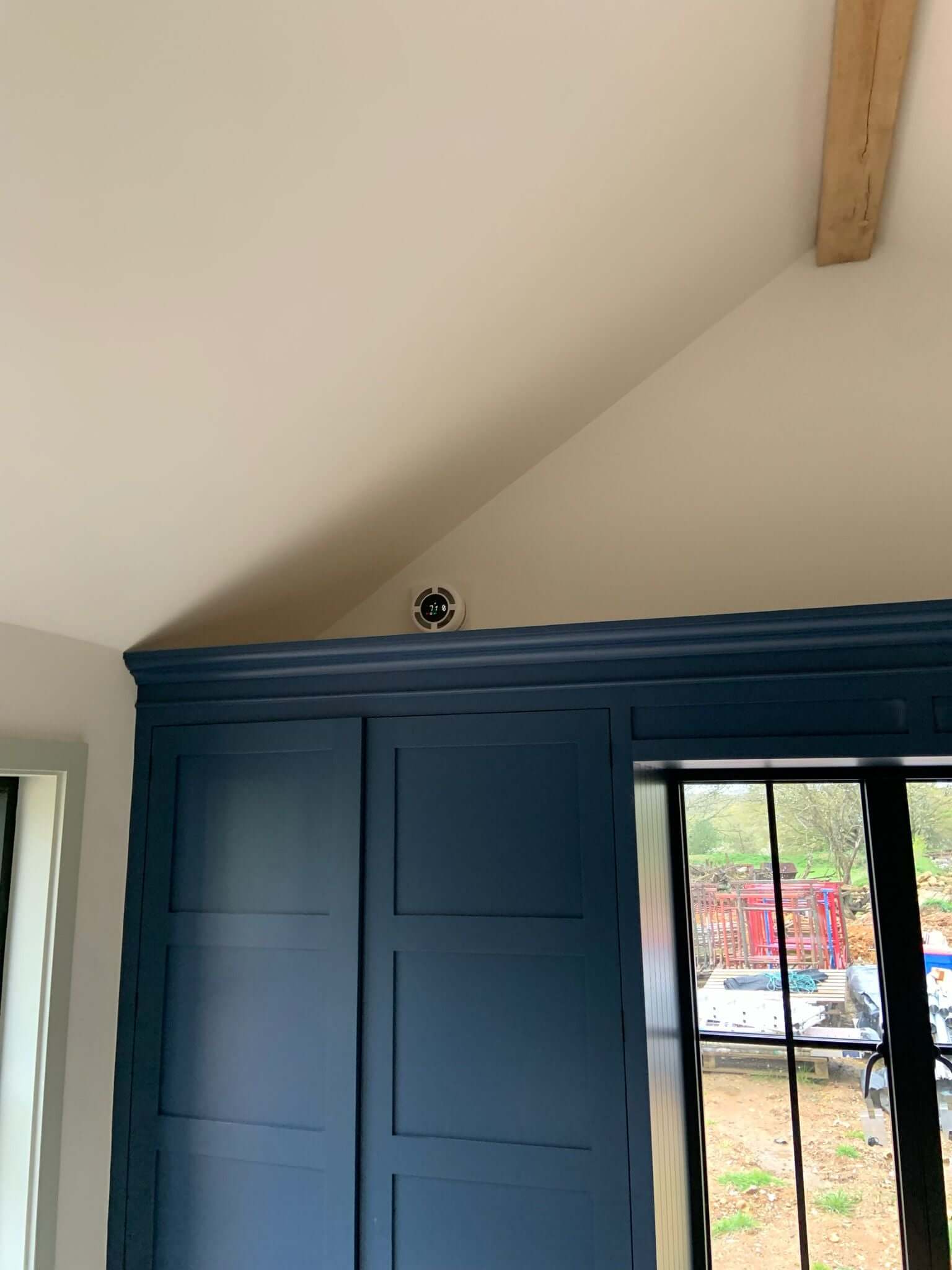 Interior view showing heat recovery ventilator installed in modern room with blue cabinetry and sloped ceiling.