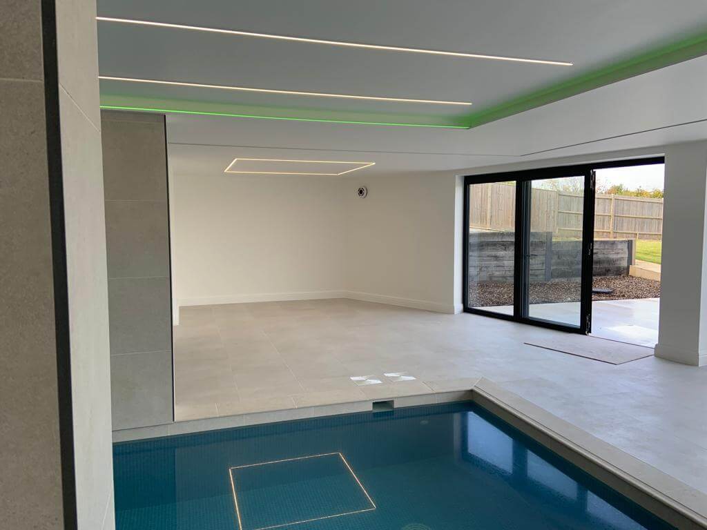 Modern indoor swimming pool with sleek design and large windows, featuring minimalistic decor and ambient lighting.