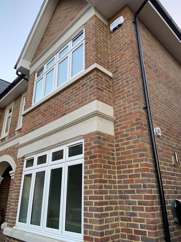 Exterior view of a brick house featuring large windows and a ventilation system, showcasing modern architecture.