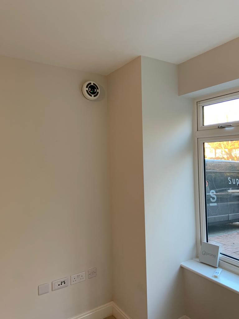 Interior view showing a heat recovery ventilator installed on the wall, enhancing ventilation efficiency in the room.