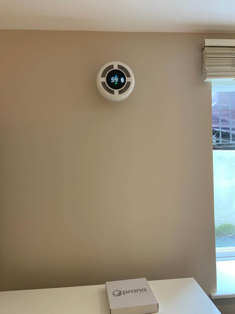 Prana 160 mini heat recovery ventilator mounted on wall, displaying humidity level for efficient ventilation.