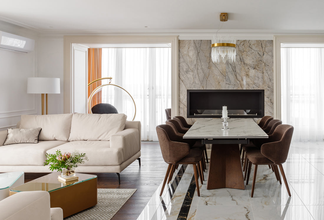 Elegant living room featuring a marble dining table, stylish chairs, and a modern sofa with large windows for natural light.