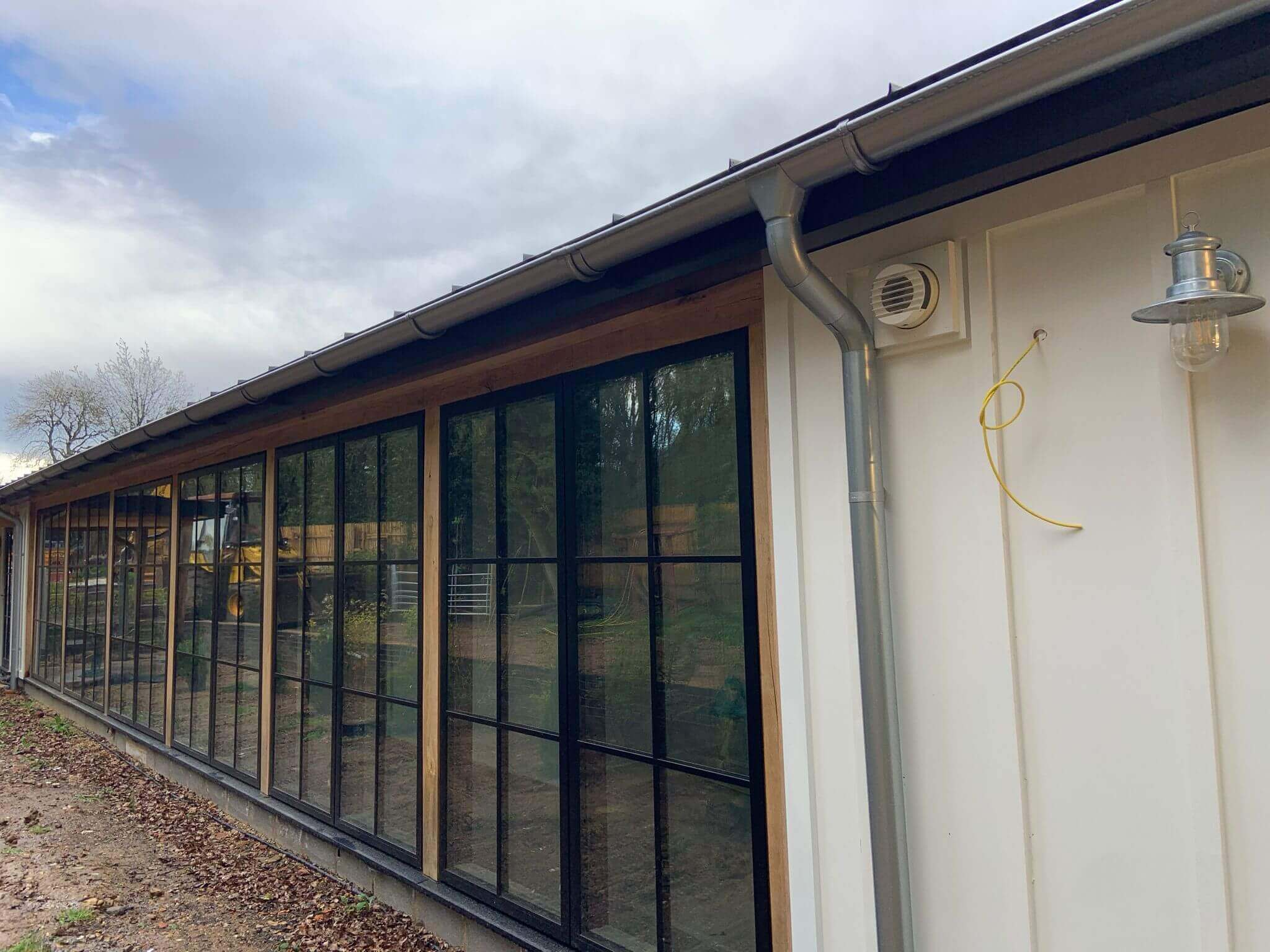 Exterior view of a modern building with large windows and a ventilation unit, showcasing energy-efficient design.