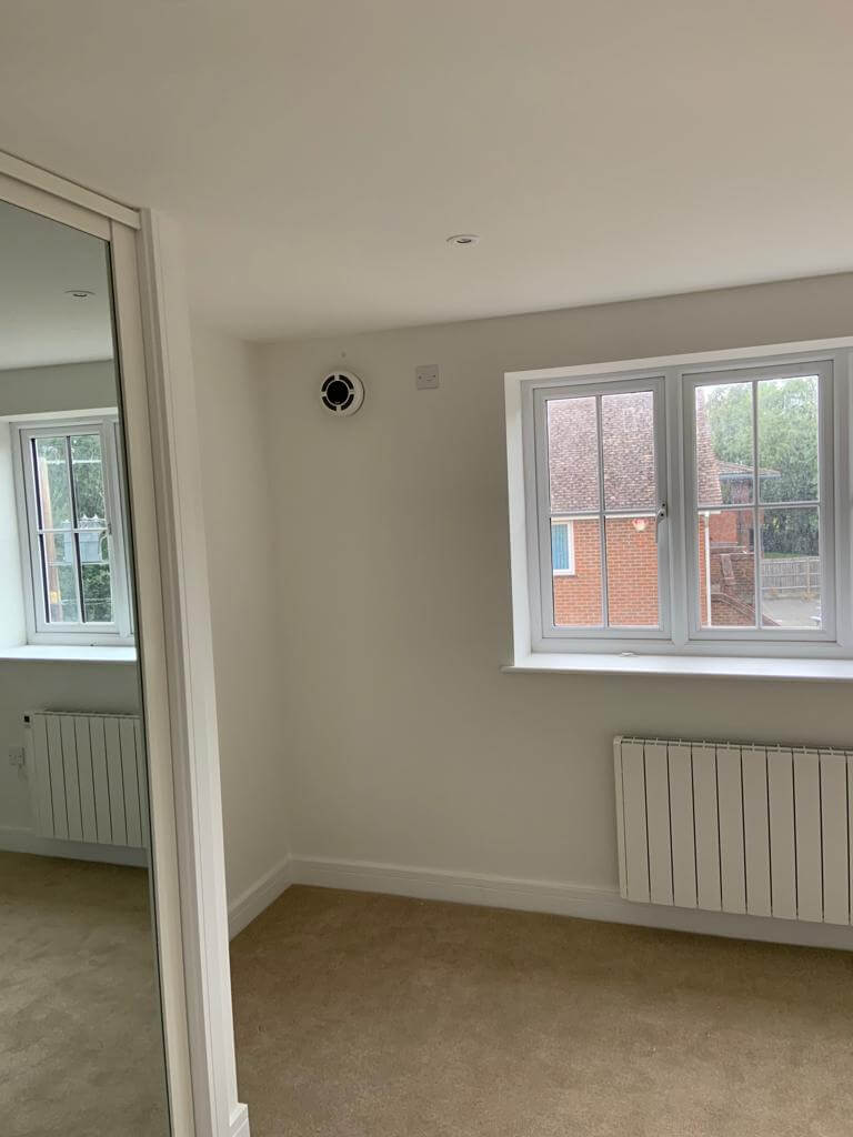 Bright room featuring a heat recovery ventilation system, windows, and radiator, ideal for energy-efficient living.