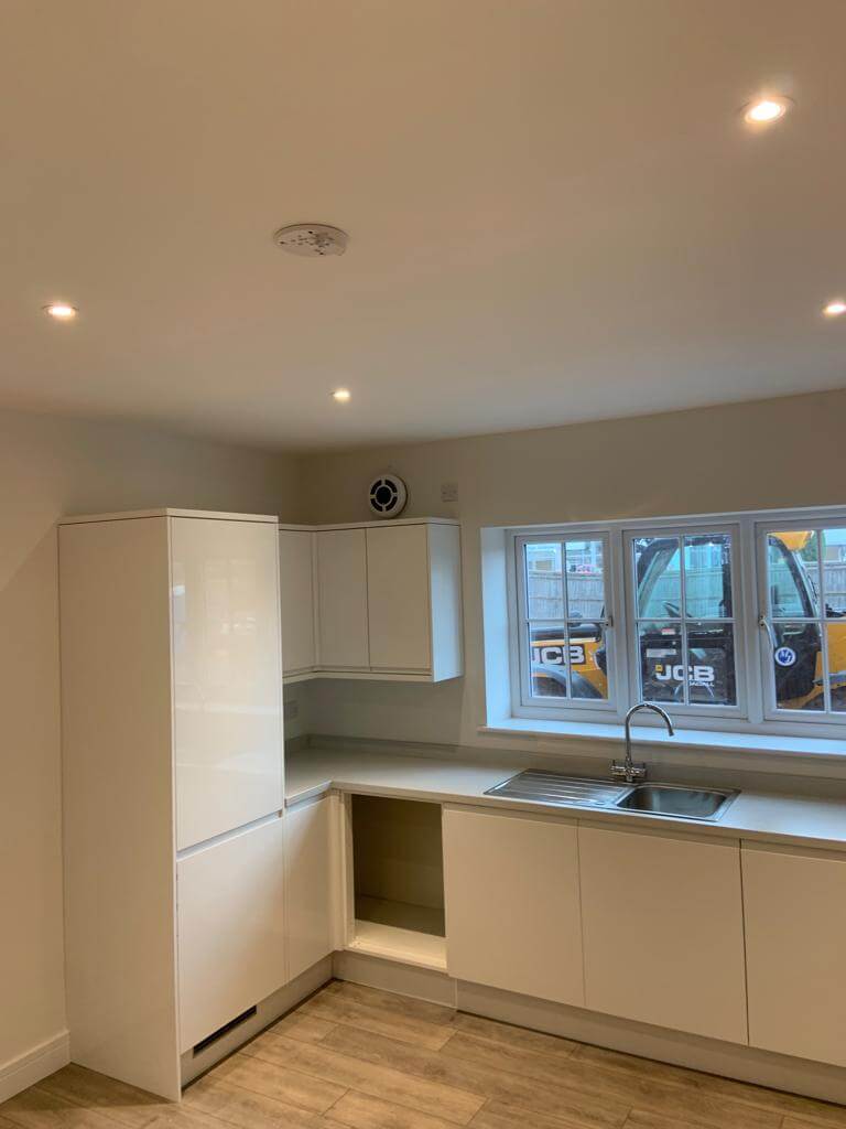 Modern kitchen featuring white cabinetry, a sink, and a ventilation system for improved air quality.
