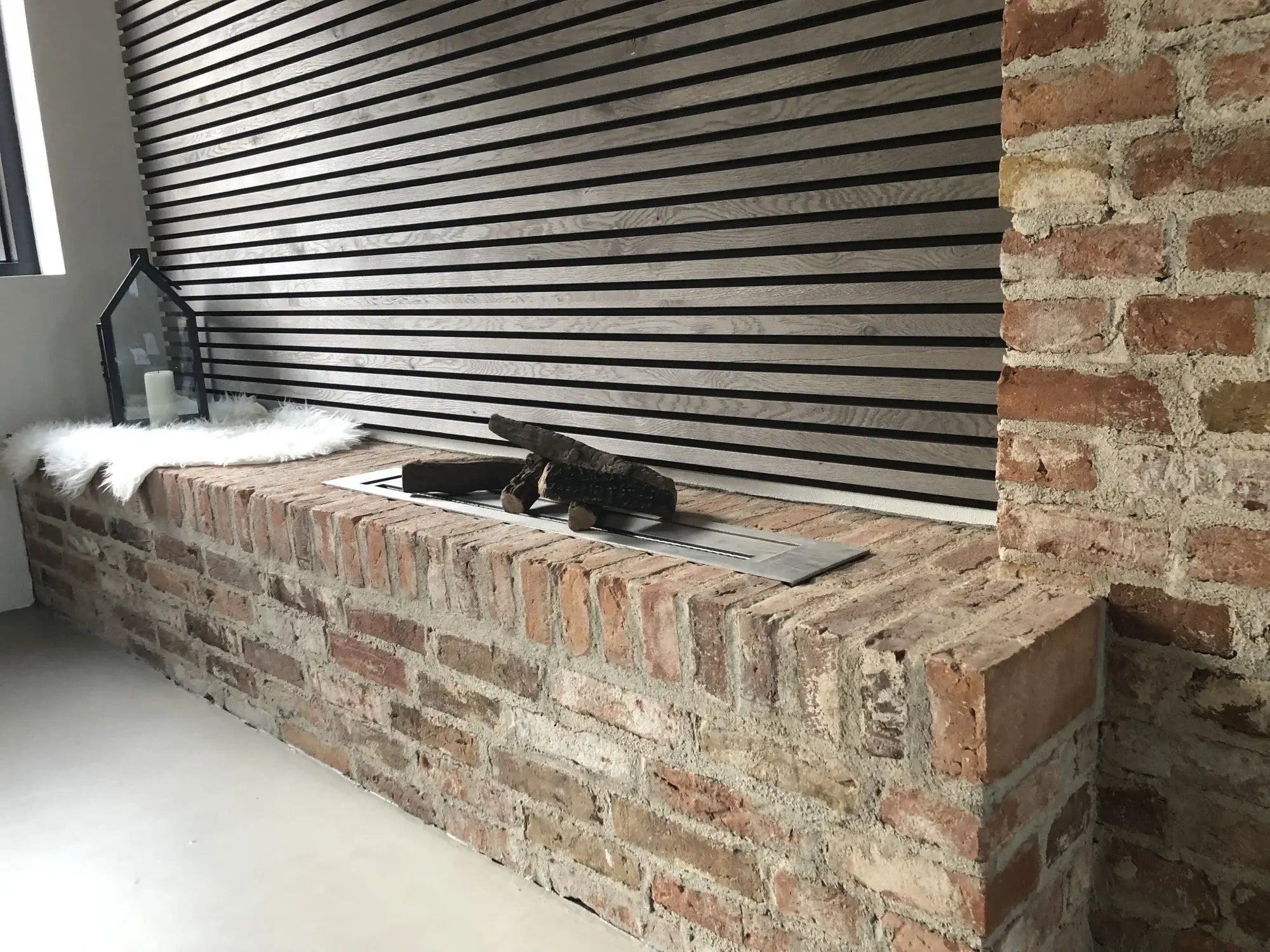 Modern bioethanol fireplace installation with a stainless steel burner set in a rustic brick wall.