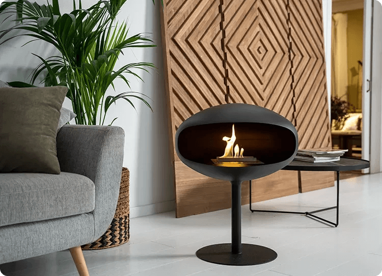 Cocoon Pedestal black bioethanol fireplace in modern living room, showcasing sleek design and warm flames.