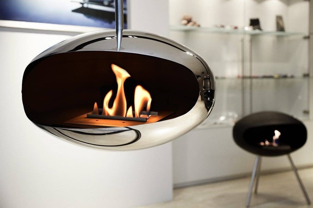 Cocoon Aeris polished steel bioethanol fireplace with vibrant flames, showcasing modern design and eco-friendly features.