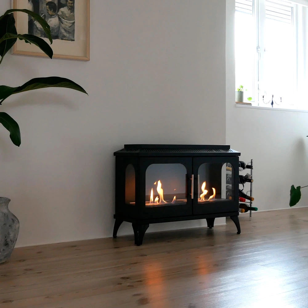 ScandiFlames Atlanta Double bioethanol stove with flames visible, set in a modern living room surrounded by plants.