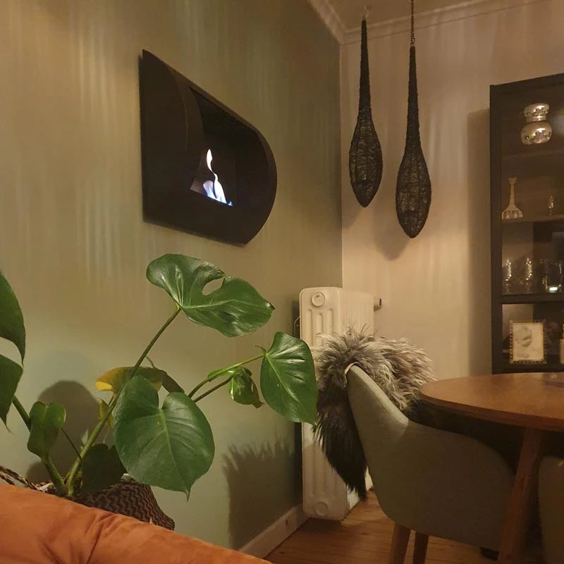 Modern black bio wall fireplace mounted in a stylish living room with plants and elegant decor.