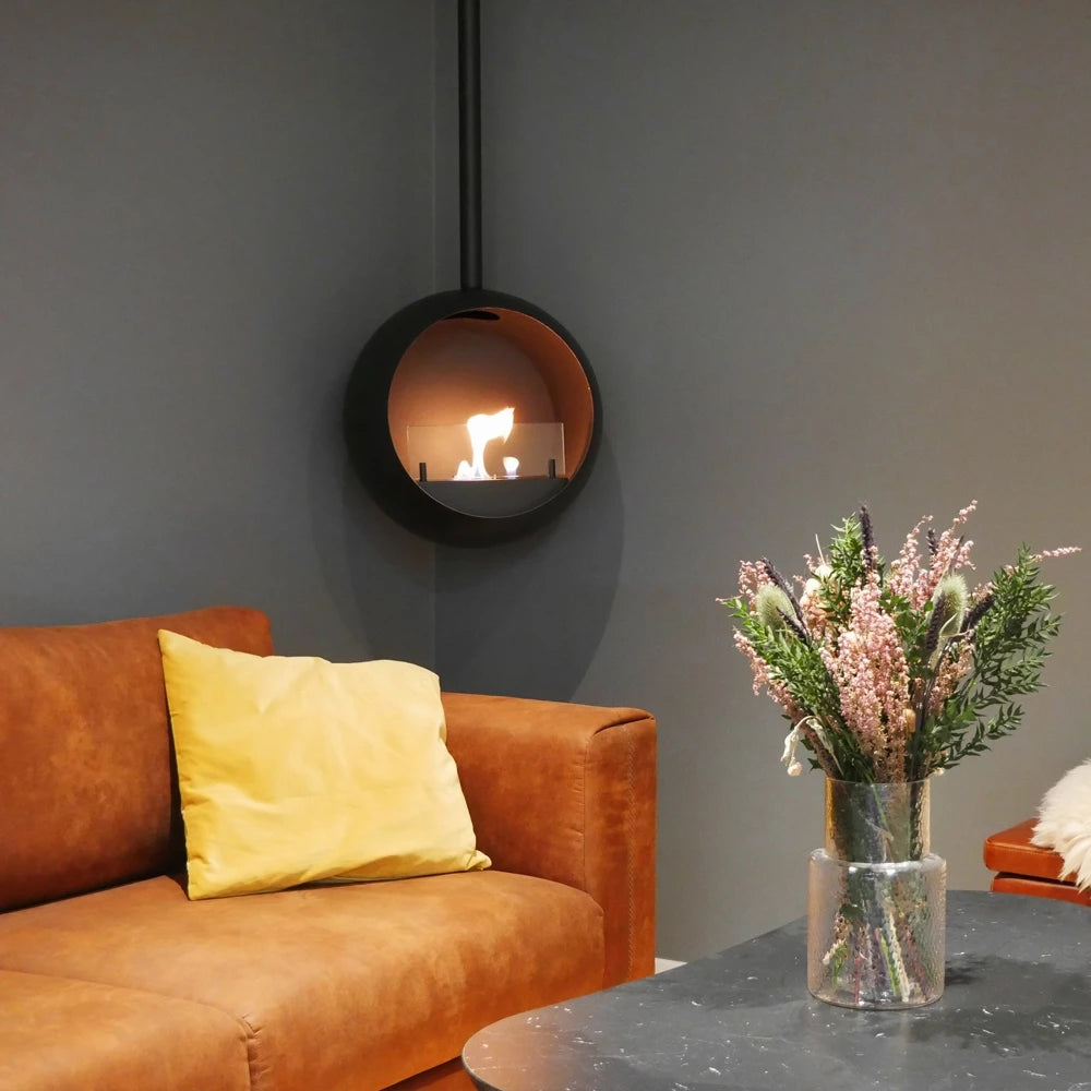 Edmonton suspended bioethanol fireplace glowing in a modern living room with brown couch and floral arrangement.