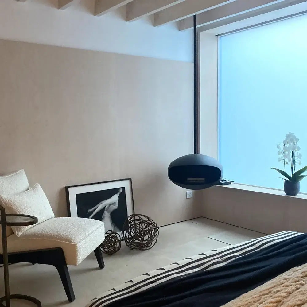 Cocoon Aeris bioethanol fireplace in matte black, elegantly suspended in a modern living room with minimalist decor.