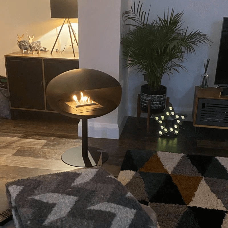 Modern bioethanol fireplace pedestal in a cozy living room setting, providing ambient flames and warmth.