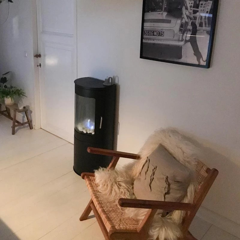 Cozy living room featuring a freestanding bioethanol fireplace next to a stylish chair with decorative pillow.
