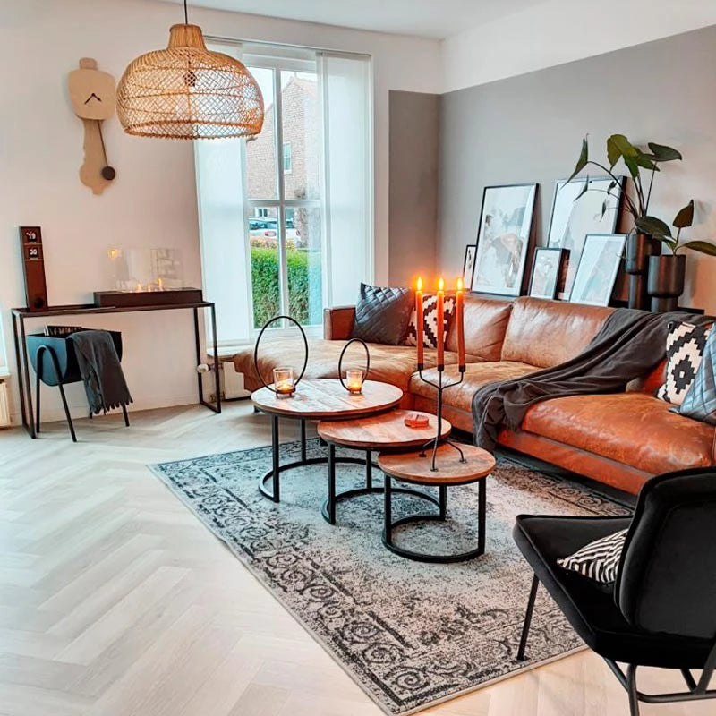 Stylish living room with a brown leather sofa, modern coffee tables, and decorative elements in a cozy setting.