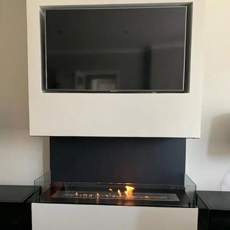 Modern bioethanol fireplace with glass panel and television above, showcasing elegant design and bioethanol flames.