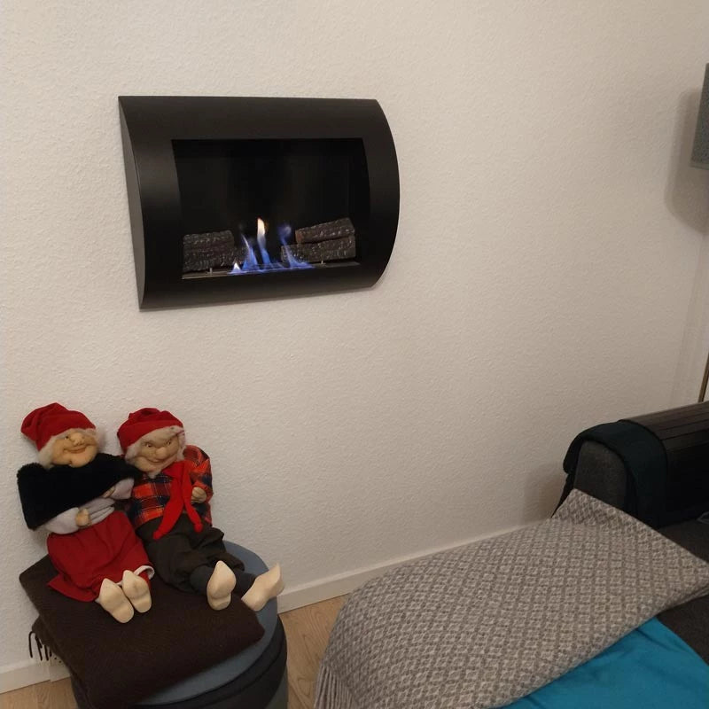 Modern black wall-mounted bio fireplace with curved design, featuring flames and decorated with festive dolls.