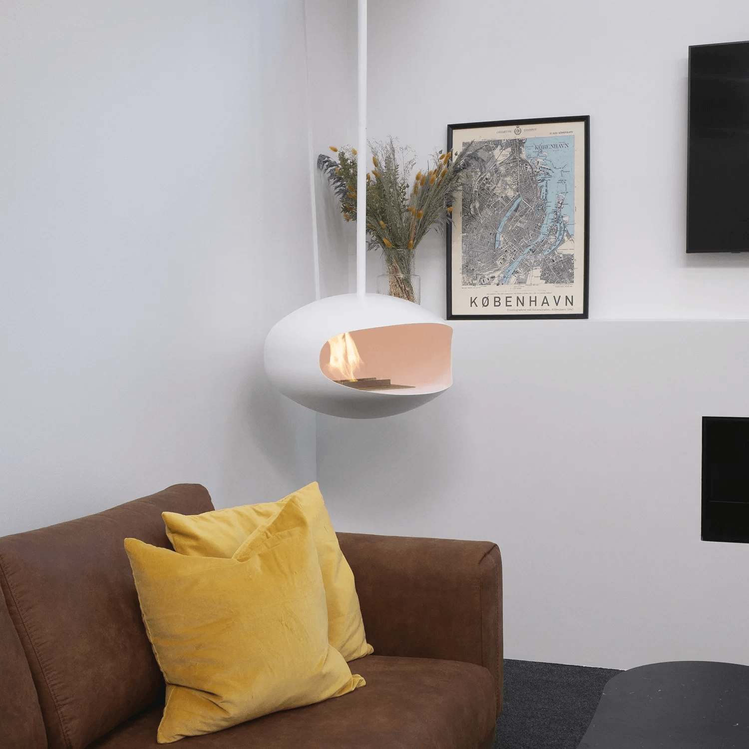 Cocoon Aeris ceiling-hung bioethanol fireplace in matte white, enhancing a cozy living room ambiance.