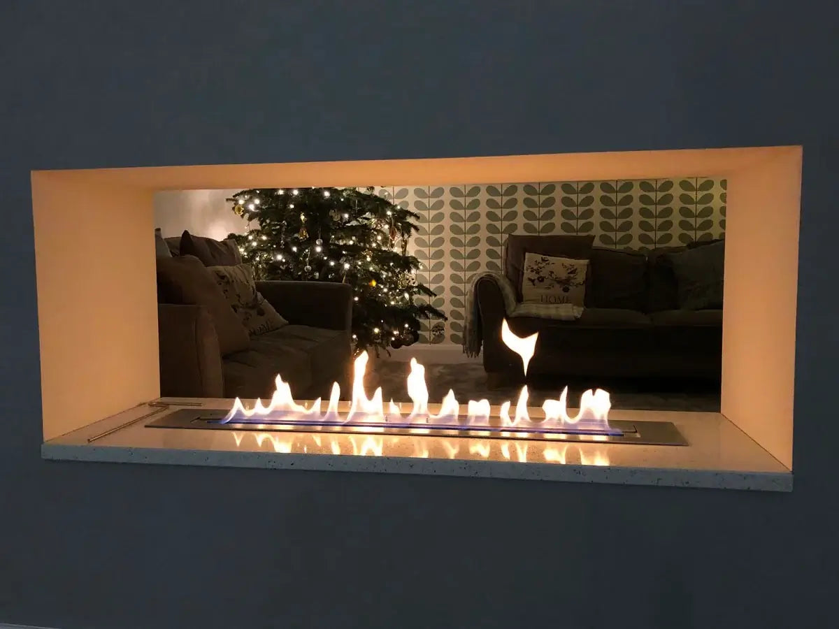 Modern bioethanol fireplace with flame, featuring a cozy living room and Christmas tree in the background.
