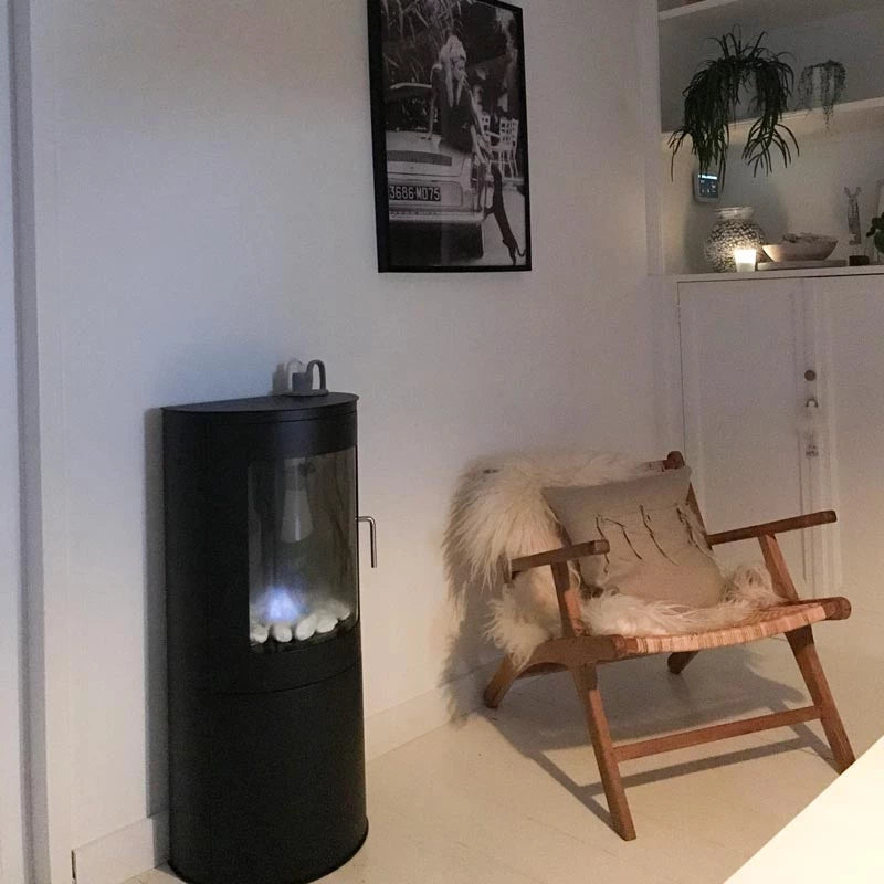 Stylish freestanding bioethanol fireplace beside a cozy chair in a modern living room.