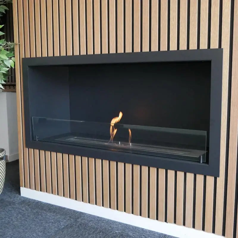 Modern built-in bioethanol fireplace with sleek black exterior and glass panel, surrounded by wood paneling.