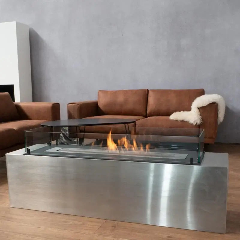 Modern bioethanol fireplace Foco Free 1200 with glass top and stainless steel base in stylish living room setting.