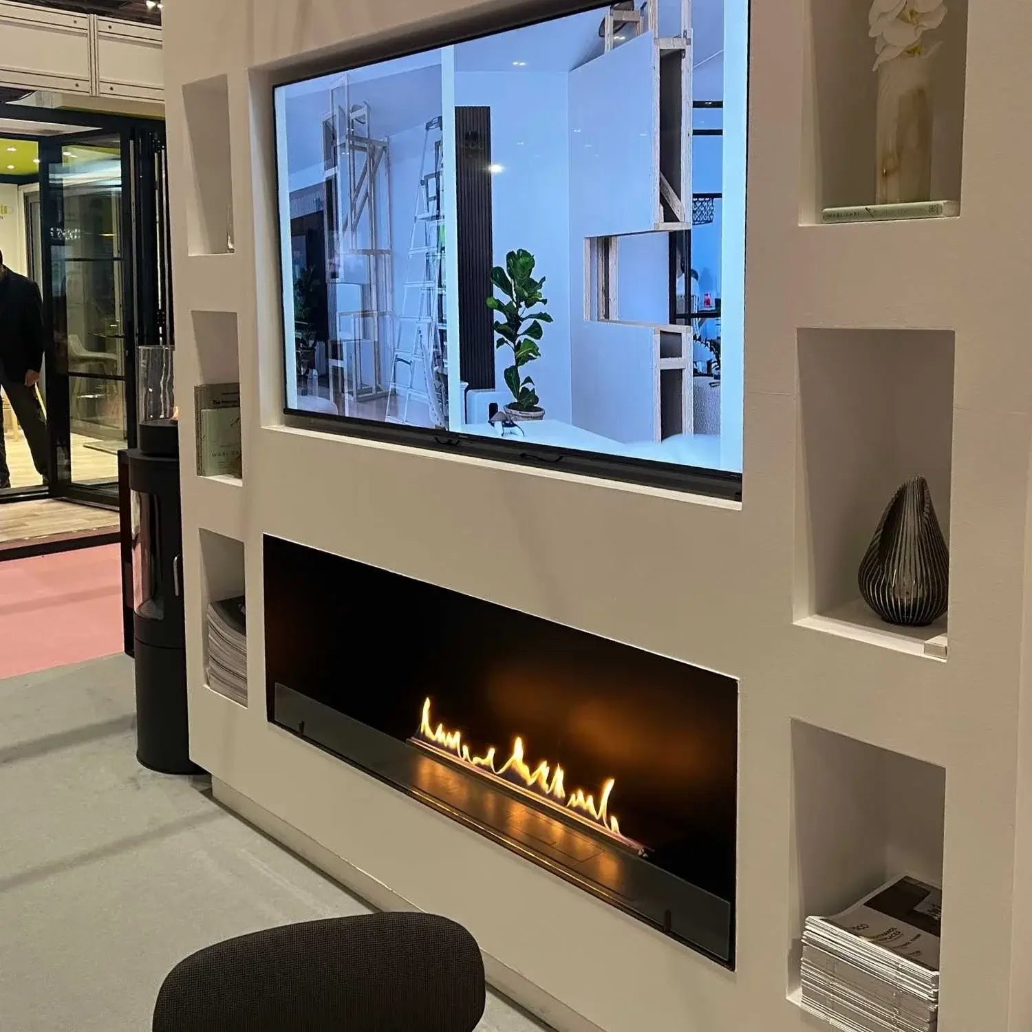 Modern bioethanol fireplace Foco One 1500 installed under a TV in a stylish interior setting, flame view.