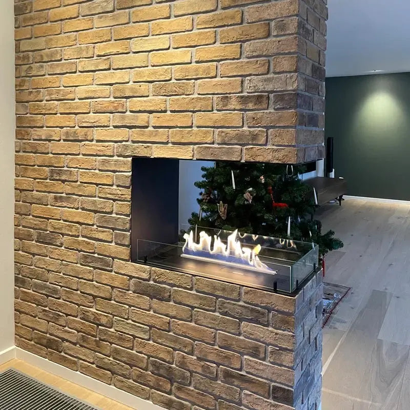 Modern bioethanol fireplace insert in a stylish brick room divider with a tree in the background, creating a cozy atmosphere.