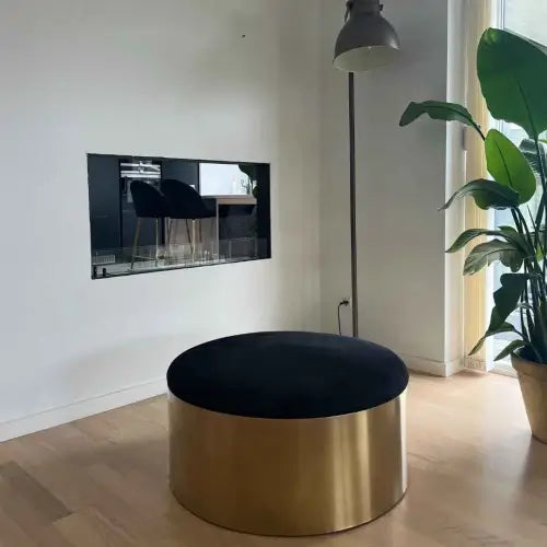Modern interior featuring a gold circular ottoman, a bioethanol fireplace insert in the wall, and a floor lamp.