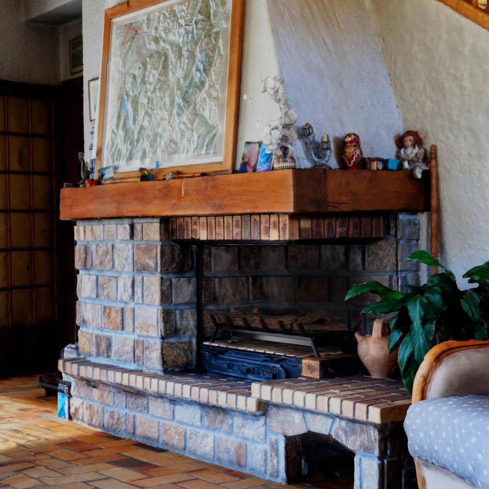 Cozy traditional stone fireplace with wooden mantel and decorative items in a warm living room setting.