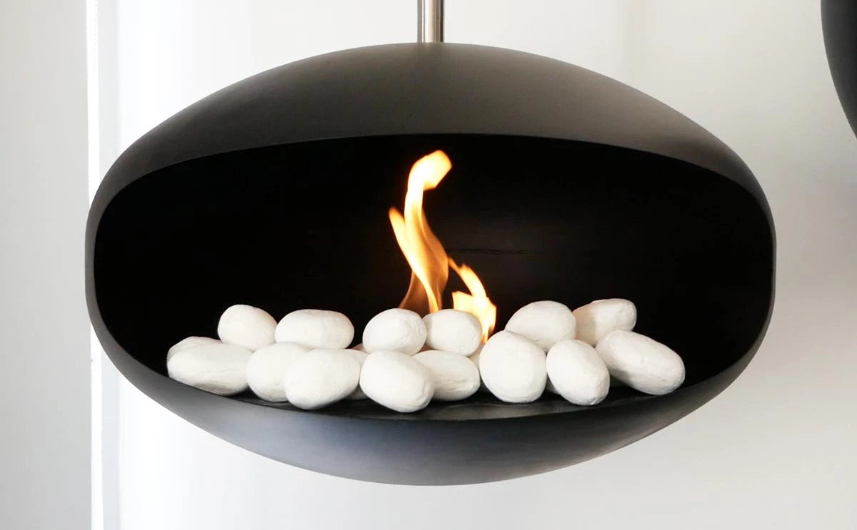 Modern bio fireplace featuring white ceramic pebbles and a vibrant flame for stylish decor.