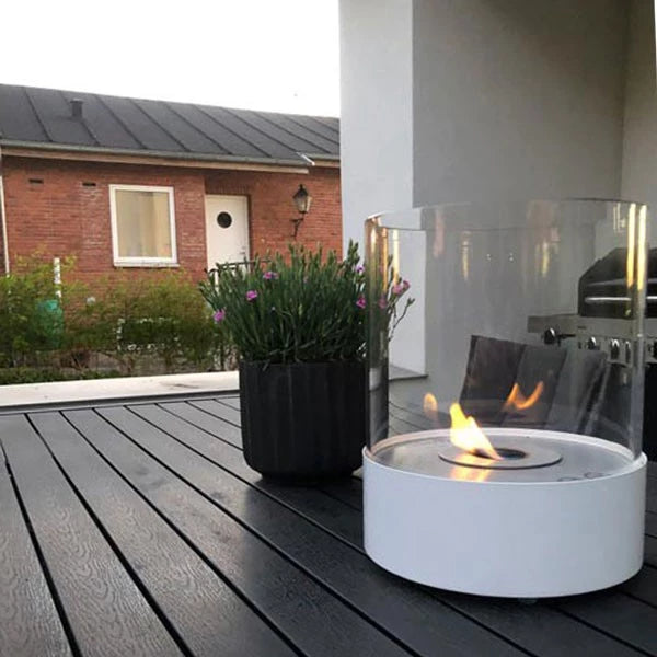 Southwark White freestanding bioethanol fireplace on a terrace with greenery in the background.