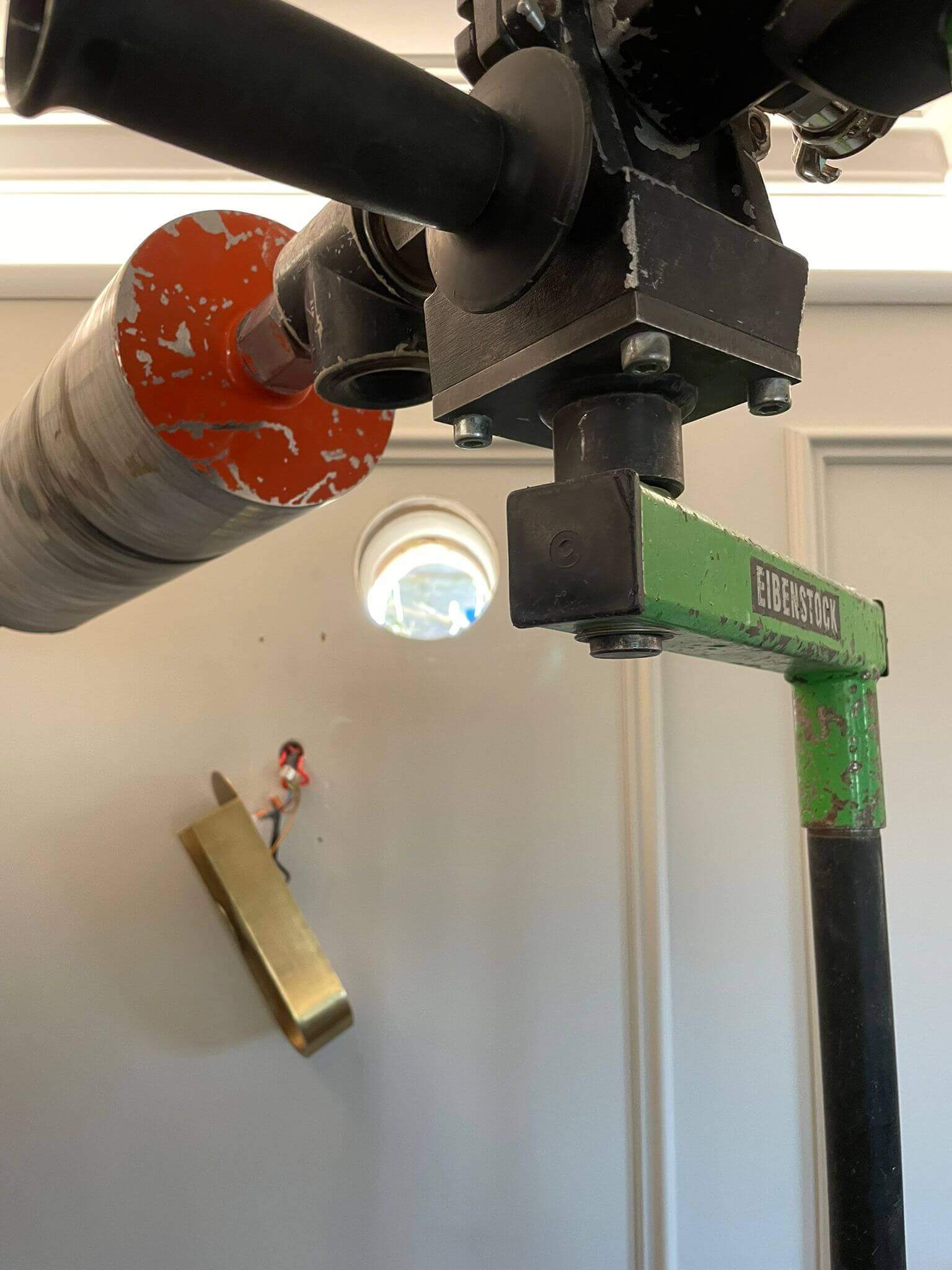 Close-up view of construction equipment, featuring a green lever and a circular saw, with tools in the background.