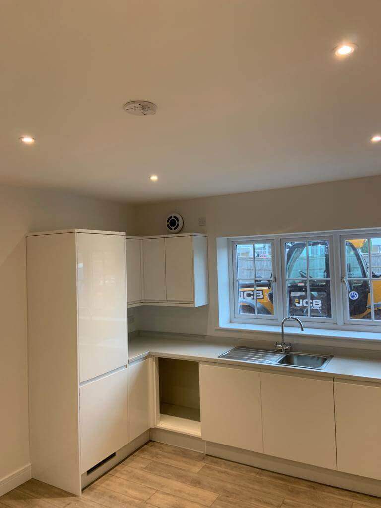 Modern kitchen interior featuring sleek white cabinets and a window providing natural light.