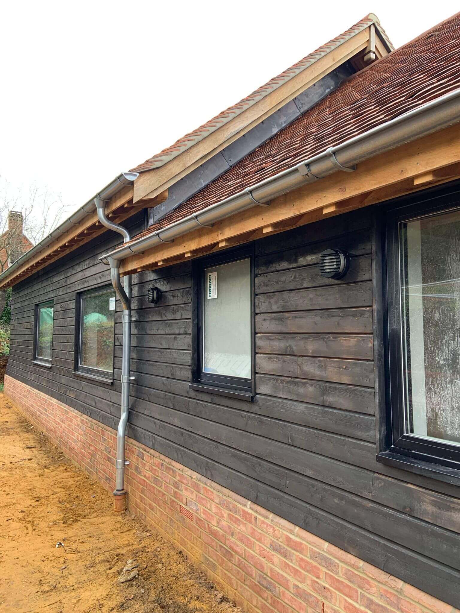 Exterior view of a modern wooden house with large windows and decorative lights.