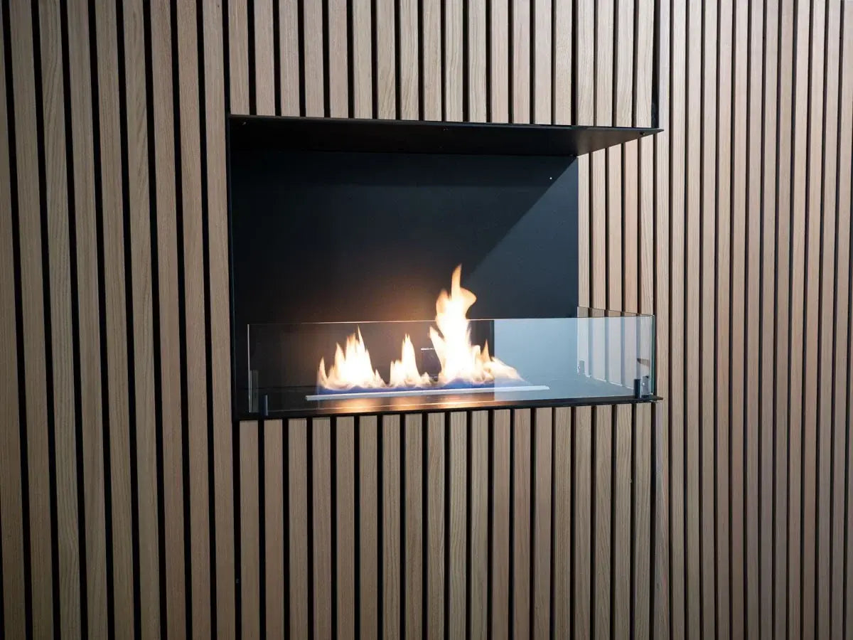 Bioethanol fireplace insert with flames visible through tempered glass, set in a modern wooden wall design.