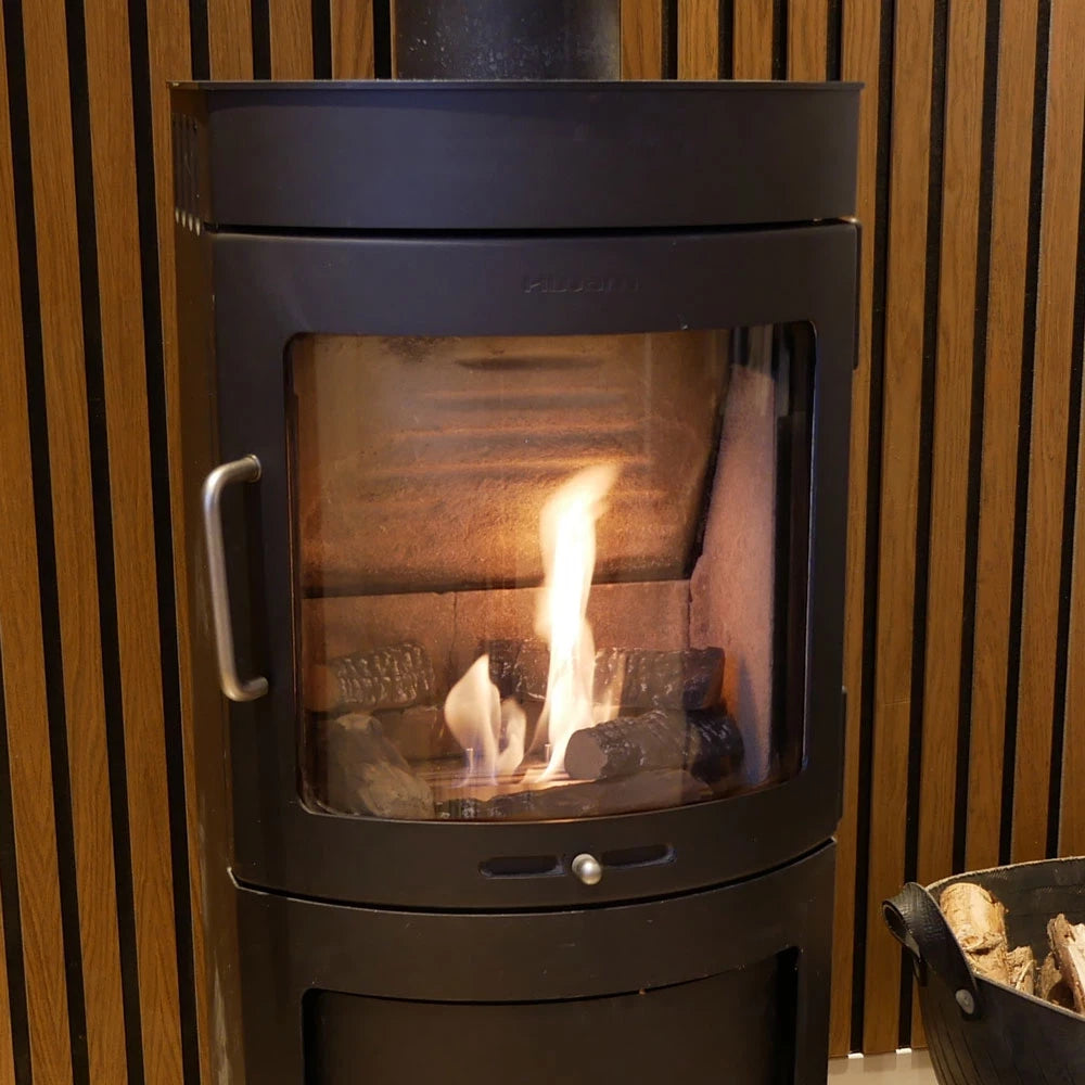 Modern bio fireplace with flames and ceramic logs, surrounded by a wooden wall for a stylish home ambiance.