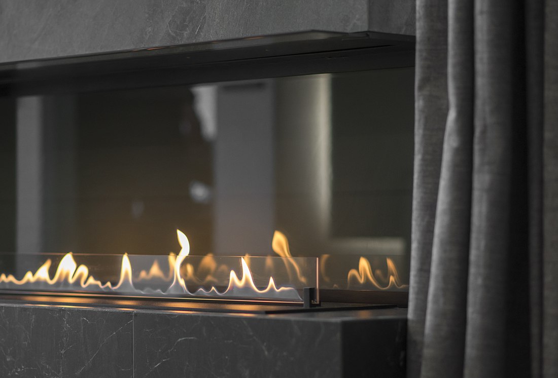 Close-up of flames in a modern bioethanol fireplace with protective glass and sleek design.