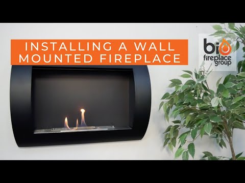 Installing a wall-mounted black bio fireplace with flickering flames, surrounded by greenery for a modern touch.