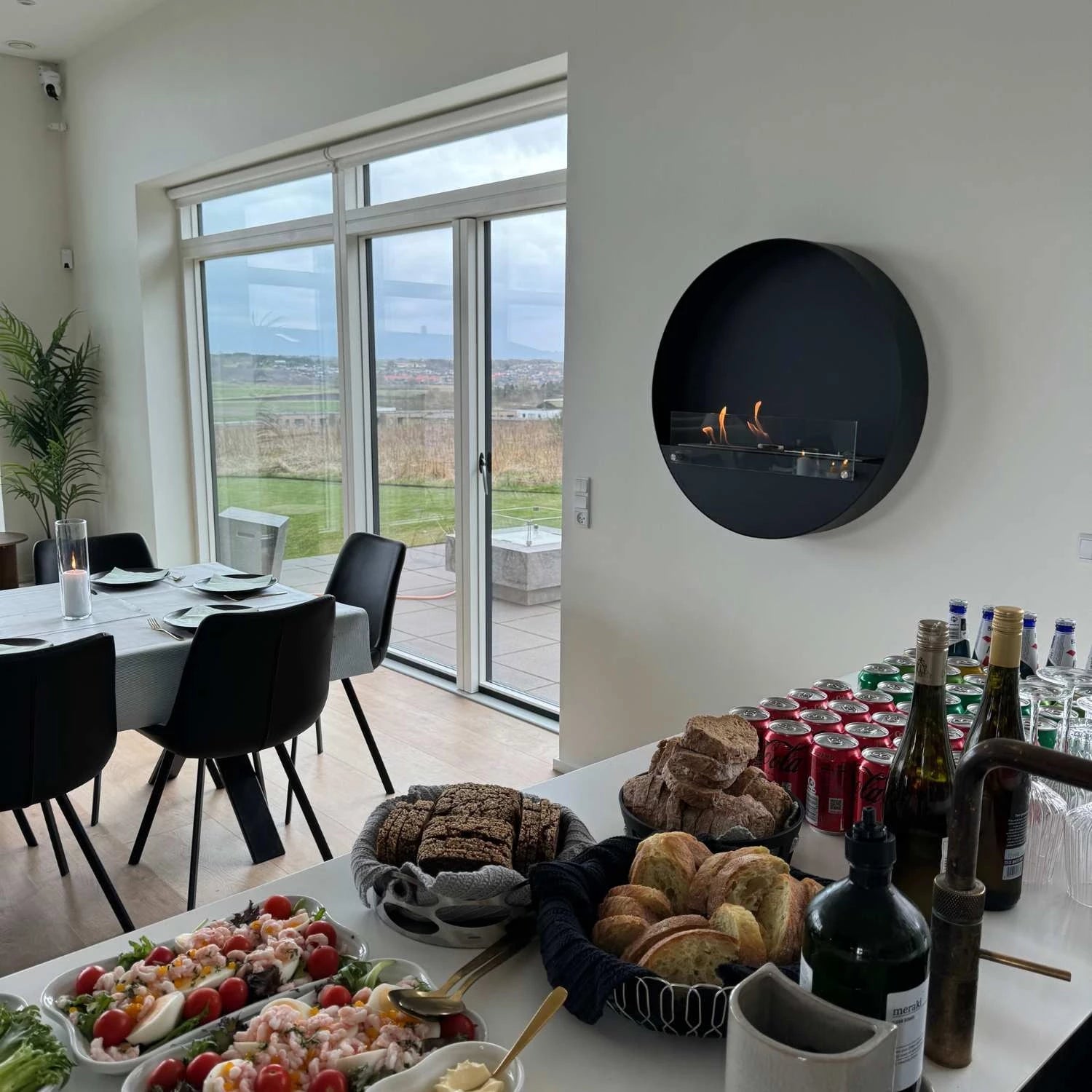 Modern dining room featuring the Delaware XL black bio fireplace and a spread of food and drinks.