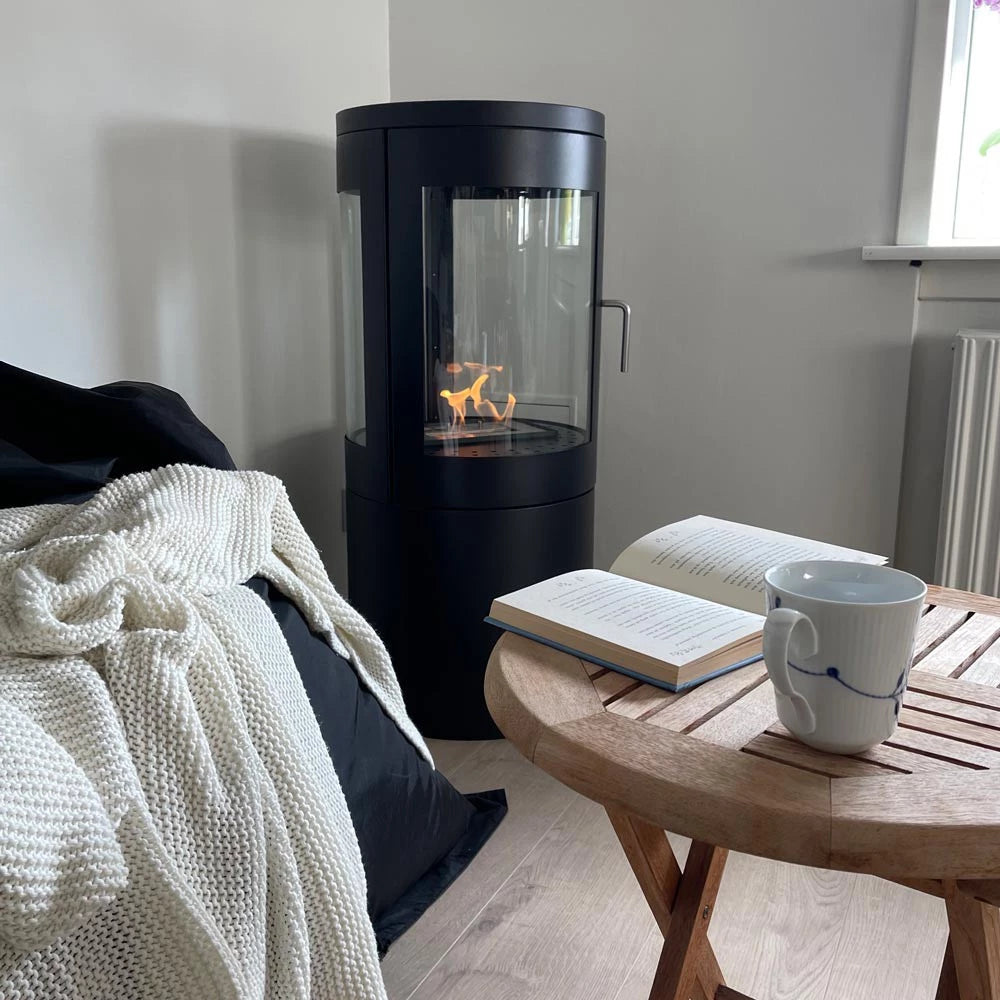 Columbus bioethanol stove with 360-degree flame view in a cozy living room setting, beside a coffee table.