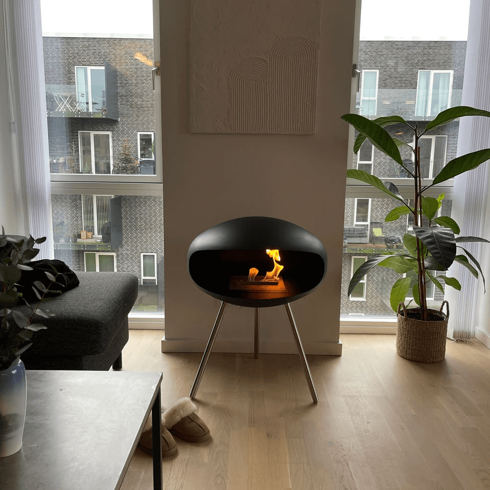 Cocoon Terra matte black bioethanol fireplace with flame, stylish modern design in a contemporary living space.
