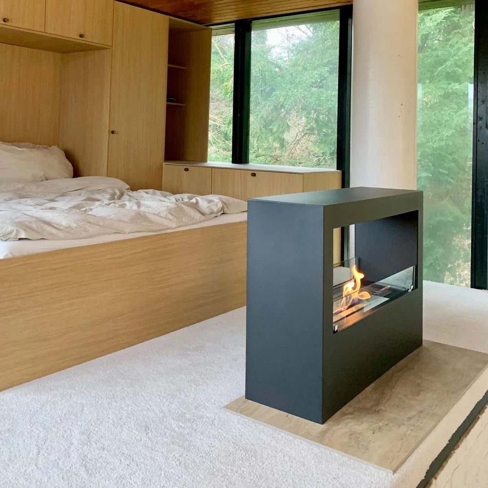 Lansing Tunnel black bioethanol fireplace in modern bedroom with natural light, serving as stylish room divider.
